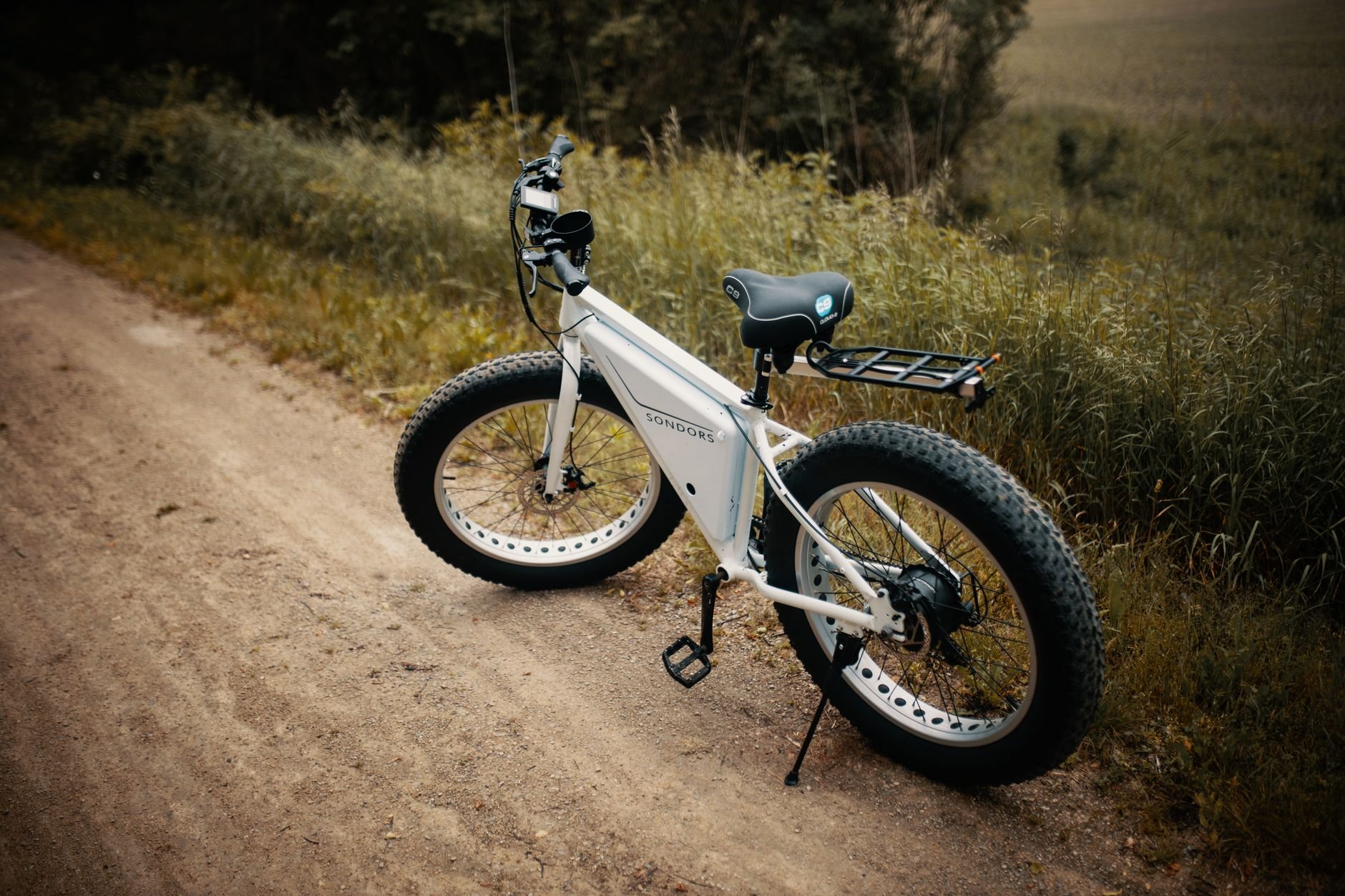 A white fat-tire electric bike parked on a dirt trail.